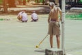 Male students use small paint rollers to paint yellow lines on the cement floor