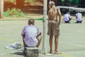 Male students use small paint rollers to paint yellow lines on the cement floor