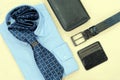 Male style concept. The layout of accessories for men. Blue shirt, tie, belt, wallet and business card holder. Yellow background. Royalty Free Stock Photo