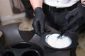 Male Stylist in gloves preparing color cream for dying hairin a container, a mask for treatment procedure in beauty salon. Hhaird