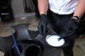 Male Stylist in gloves preparing color cream for dying hairin a container, a mask for treatment procedure in beauty salon. Hhaird