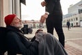 Unrecognizable man in tuxedo give money donation to homeless