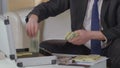 Male in suit opens suitcase to take wads of dollars out of it, illegal bribery