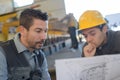 Male supervisor with worker discussing over blueprints in industry Royalty Free Stock Photo