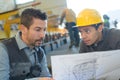 Male supervisor with worker discussing over blueprints in industry Royalty Free Stock Photo