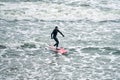 Male surfer in black swimsuit with red surfboard in sea waves