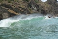 A male surfer in a black wetsuit watches an empty wave break at Piha Beach, Piha, Auckland, New Zealand