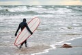 Male surfer in swim suit walking along sea with surfboard Royalty Free Stock Photo