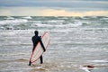 Male surfer in swim suit walking along sea with surfboard