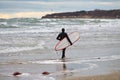 Male surfer in swim suit walking along sea with surfboard Royalty Free Stock Photo