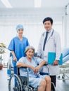 Male surgeon doctors and professional female nursing assistants take care senior woman patients in wheelchair.