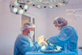 Male surgeon performs surgical procedures in the operating room, while his assistant monitors the patient condition Royalty Free Stock Photo