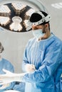 Male surgeon puts on surgical gloves and disinfects before operation. Surgeon with headlight is preparing for surgery in Royalty Free Stock Photo