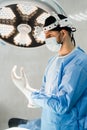 Male surgeon puts on surgical gloves and disinfects before operation. Surgeon with headlight is preparing for surgery in Royalty Free Stock Photo