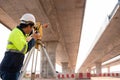 A male surveyor engineers worker making measuring under the expressway with theodolite on road works. Survey engineer at road