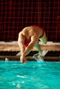 A male swimmer dives into the pool with his head into the water, the start of the swim in the pool. Royalty Free Stock Photo