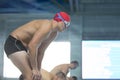 A male swimmer in a swimming cap and goggles on the background of the pool