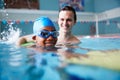 Male Swimming Coach Giving Boy Holding Float One To One Lesson In Pool