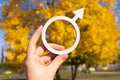 Male symbol of Mars in the hand on the background of autumn foliage