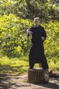 A male tai Chi master practices qigong in nature standing on a stump Royalty Free Stock Photo