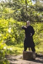 A male tai Chi master practices qigong in nature standing on a stump Royalty Free Stock Photo