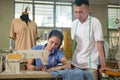 Male tailor stands beside and sees the female tailor using the sewing machine Royalty Free Stock Photo