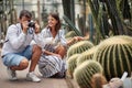 Male taking a photo of cactus in botanical garden with female guide beside him