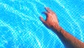 Male tanned hand in a pool of blue water. Relax, spa and recreation concept background