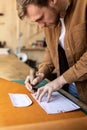 Male tanner making cutting scheme of bag working at leather workshop. Handcrafted creating