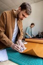 Male tanner making cutting scheme of bag working at leather workshop. Handcrafted creating