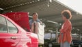 Male taxi driver helping woman with suitcase on the parking.