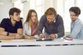 Male teacher in class helps group of highschool students working on digital tablet. Royalty Free Stock Photo