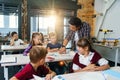 Teacher helping school kids with test tasks in classroom at primary school.