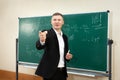 The male teacher used white chalk to write on the blackboard to teach students in a class Royalty Free Stock Photo