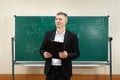 The male teacher used white chalk to write on the blackboard to teach students in a class. Royalty Free Stock Photo