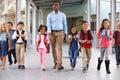 Male teacher walking in corridor with elementary school kids Royalty Free Stock Photo