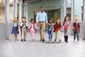 Male teacher walking in corridor with elementary school kids Royalty Free Stock Photo