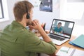 Male teacher wearing headphones having a video call with male student on laptop at home Royalty Free Stock Photo