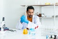 A male teacher in white lab coat with rubber gloves with many laboratory tools on shelves and table. Looking at blue and yellow Royalty Free Stock Photo