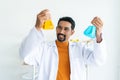 Male teacher in white lab coat with safety glasses with laboratory tools background in university science classroom holding two Royalty Free Stock Photo