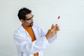 A male teacher in white lab coat with safety glasses looking serious at mixed chemical liquid in bottle and pipette in hand. Royalty Free Stock Photo