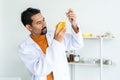 Male teacher in a white lab coat wearing safety goggles looked seriously at bottle of liquid chemicals and pipette in hand.