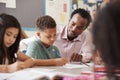 Male teacher working with elementary school boy at his desk Royalty Free Stock Photo