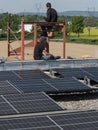 Male team engineers installing stand-alone solar photovoltaic panel system. Electricians mounting blue solar module on roof of