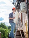 Male technician checking air conditioning system with instructions