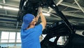 Male technician is repairing a bootlid of a car