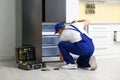 Male technician repairing broken refrigerator