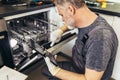 Male Technician Repairing Dishwasher In Kitchen Royalty Free Stock Photo