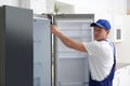 Technician with screwdriver repairing refrigerator in kitchen Royalty Free Stock Photo