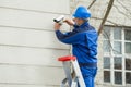 Male Technician Standing On Stepladder Fitting CCTV Camera